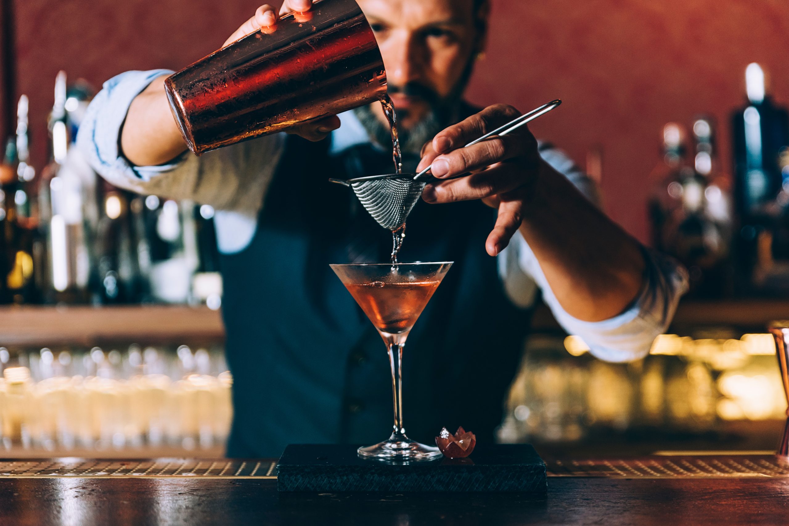 Barman is making cocktail at night club.